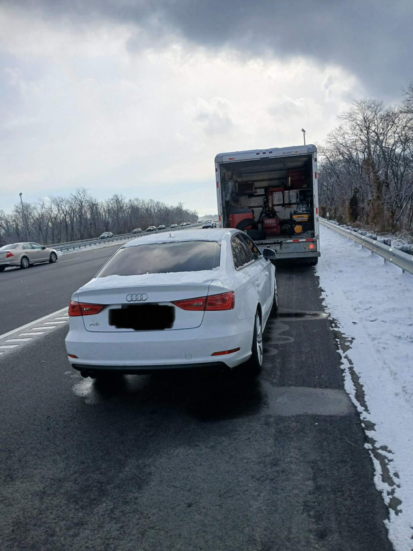 Roadside tire service on an Audi A3 along a snowy NJ highway